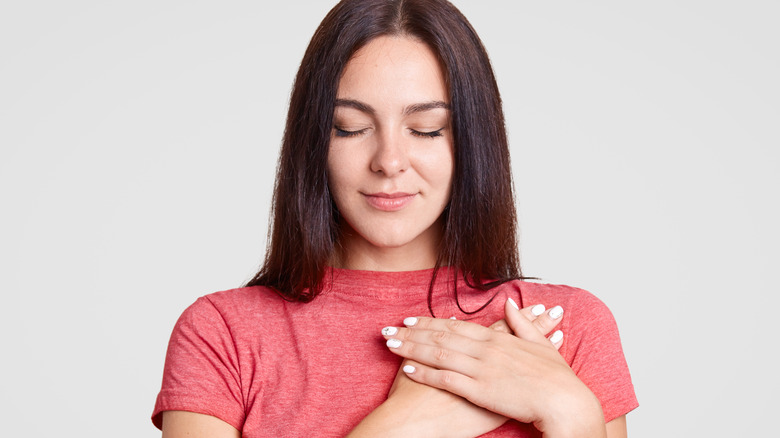 Woman holding hands close to heart