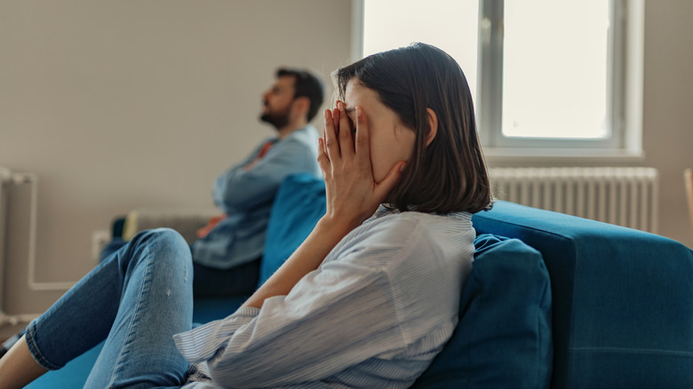 Woman looks away from man, crying