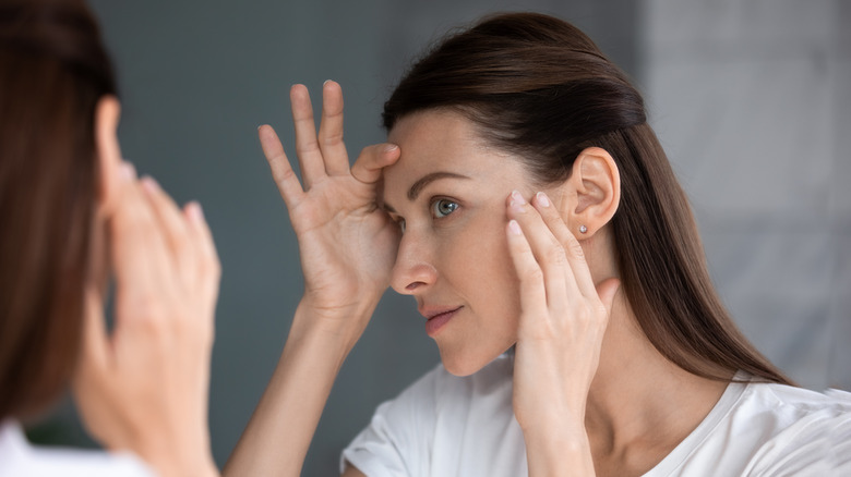 Woman examining her skin in mirror