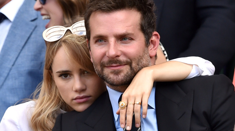 Suki Waterhouse with her arm around Bradley Cooper