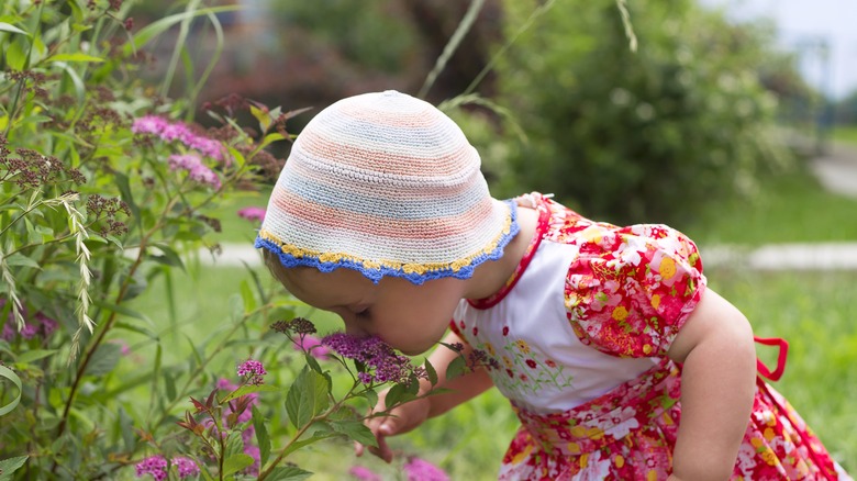 baby smelling flowers