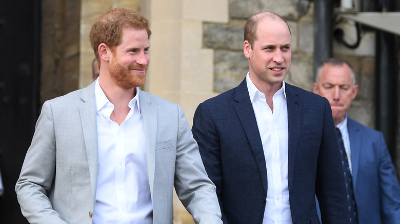 Prince Harry smiling and walking with Prince William