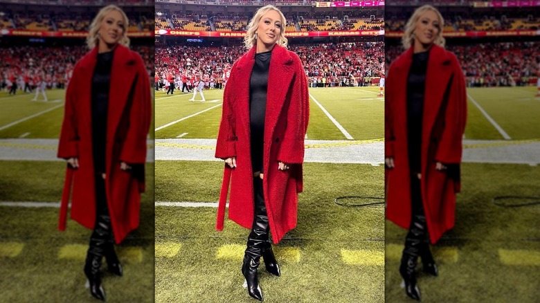 Pregnant Brittany Mahomes posing on football field in red coat