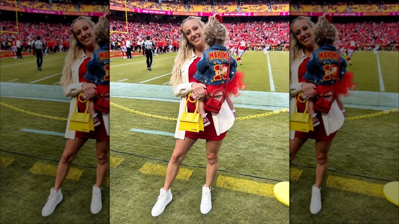 Brittany Mahomes holding her daughter on football field and smiling