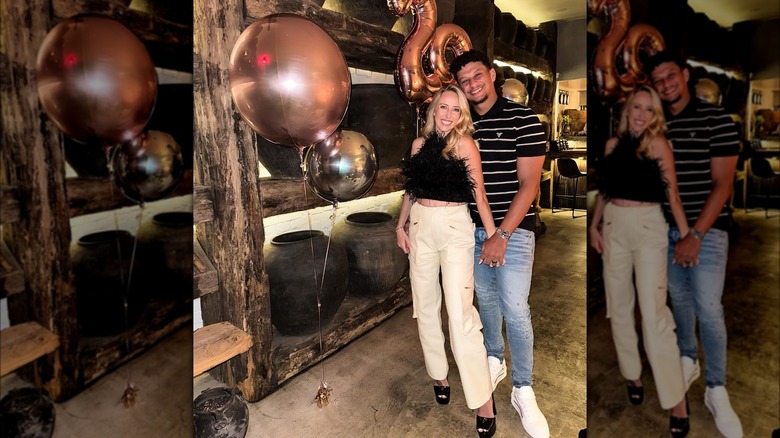 Brittany and Patrick Mahomes posing in front of 29th birthday balloons