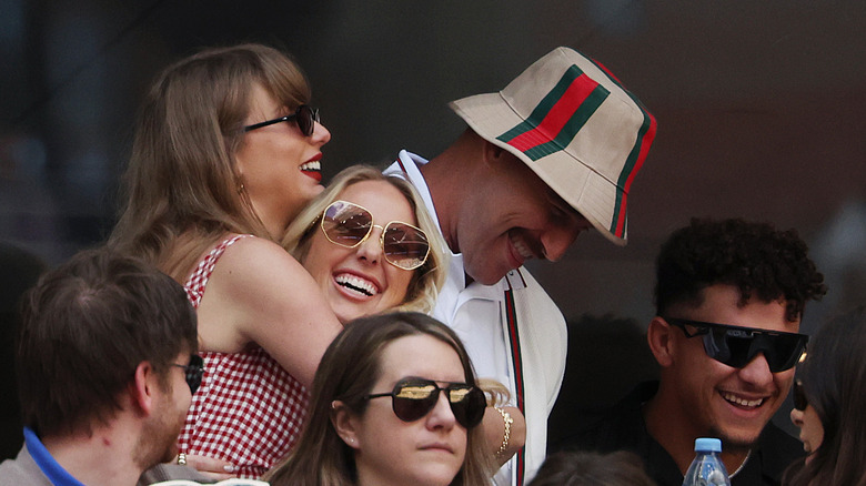 Taylor Swift and Brittany Mahomes hugging while Travis Kelce and Patrick Mahome smile during the US Open