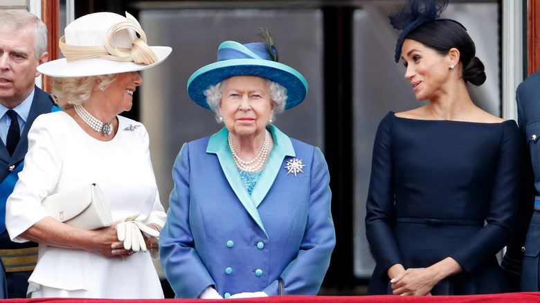 Camilla Parker Bowles, Queen Elizabeth, and Meghan Markle standing on the balcony at Buckingham Palace