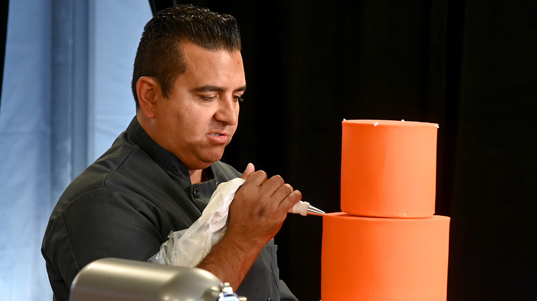 Buddy Valastro decorating a tiered cake.