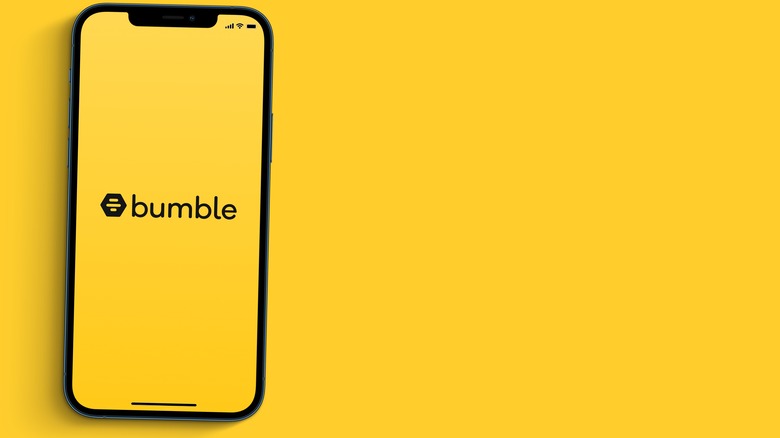 A phone with the Bumble logo on the screen and a yellow background 