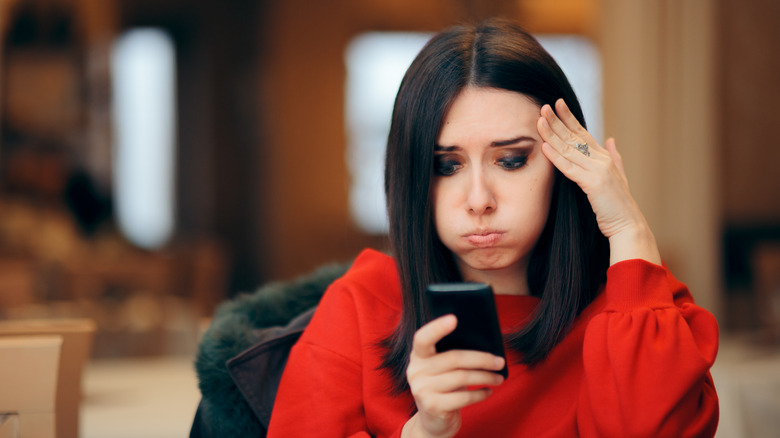 An upset woman looking at her phone 