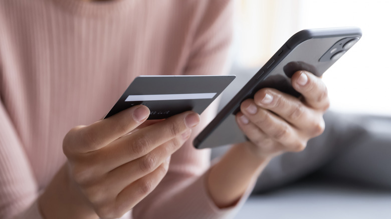 Woman holding credit card and phone