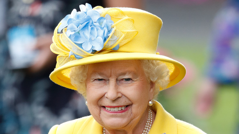 The queen smiles in an all-yellow outfit