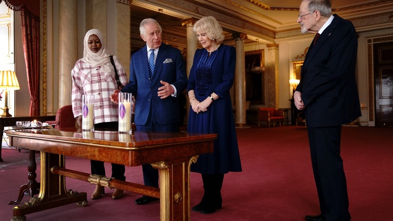 Camilla, Queen Consort smiles with King Charles III and associates