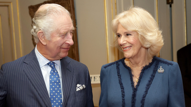 King Charles and Queen Camilla smiling at each other