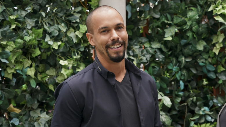 Bryton James smiling in front of hedge