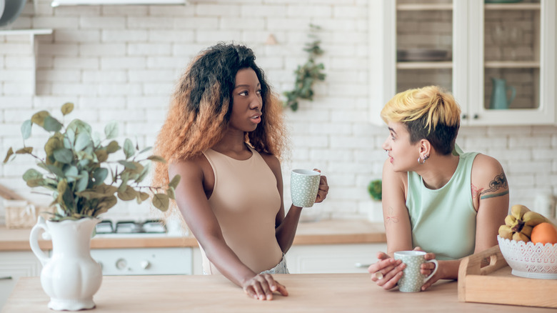 A couple holding cups at table talking