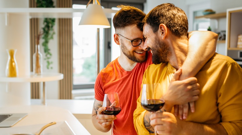 Gay couple snuggling with wine