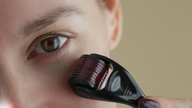 Woman using a dermaroller under her eyes