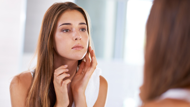 Woman looking at her face in the mirror