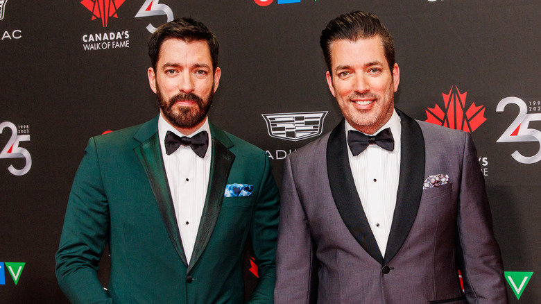 Jonathan and Drew Scott posing in suits at a premiere event