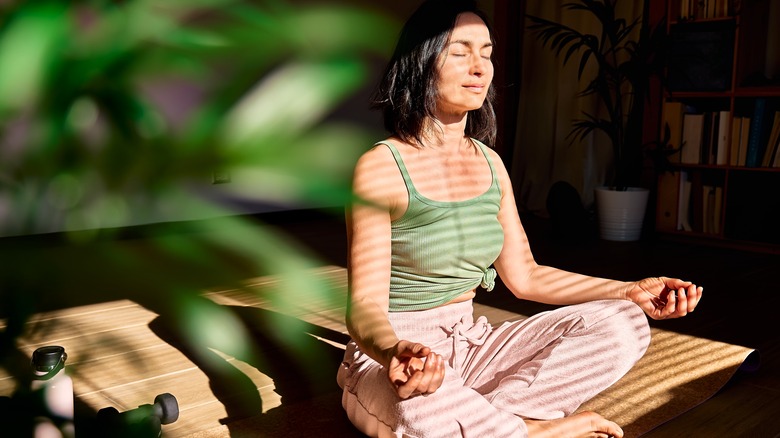 Woman practicing mediation in front of window