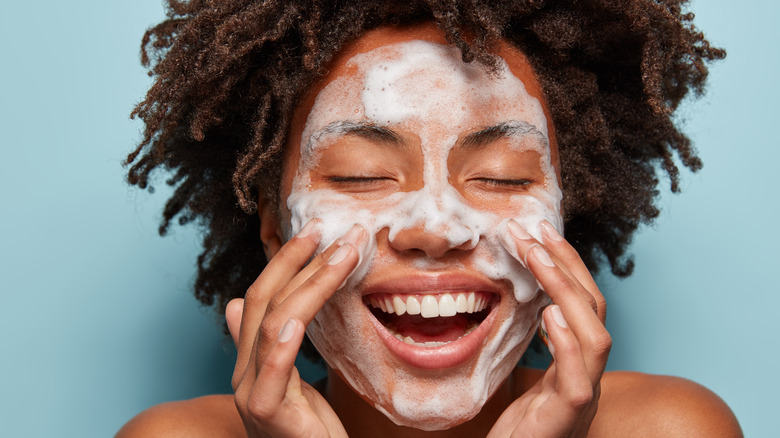 woman lathering face with cleanser