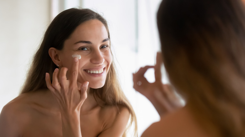 Woman applying cream to face