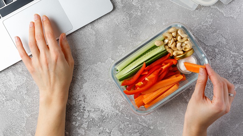 Woman snacking while using her laptop