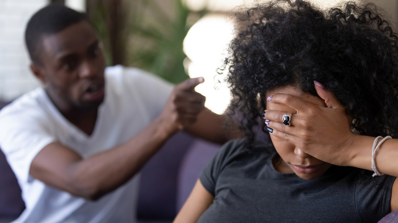 Woman covering her face, being yelled at by partner