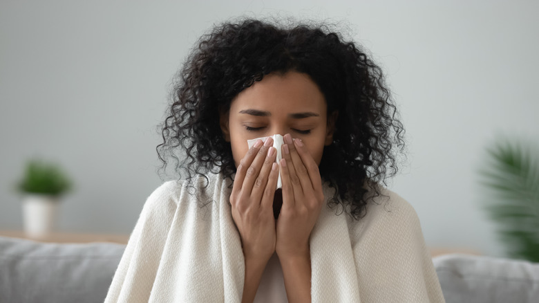 woman in blanket blowing nose