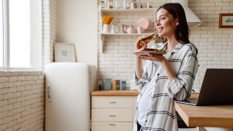 Pregnant woman eating sandwich