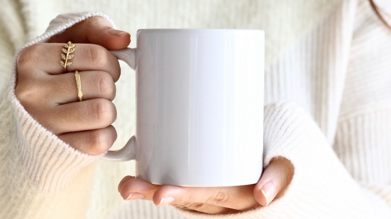 Woman holds cup of tea with rings on