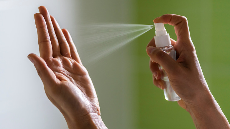 Person spraying hand sanitizer on hands