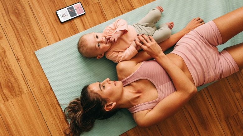 mom laying on a yoga mat with baby