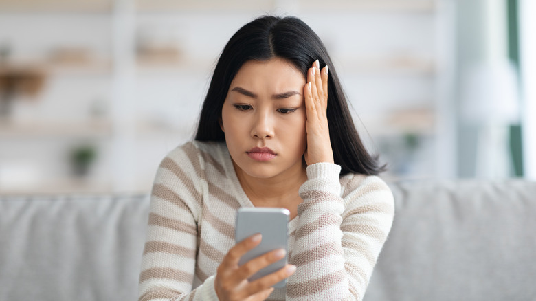 Worried woman looking at her phone