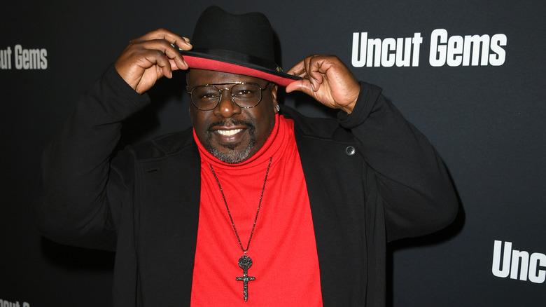 Cedric The Entertainer fixing his hat at an event