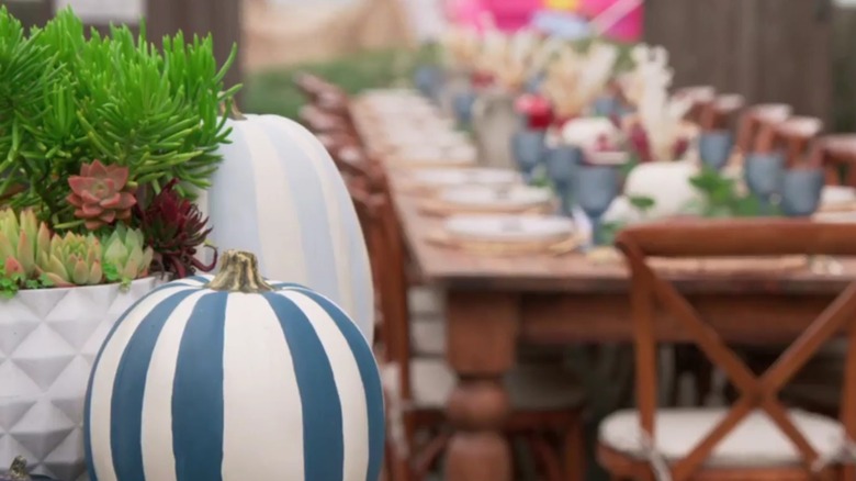 A pumpkin and succulent display next to a long table