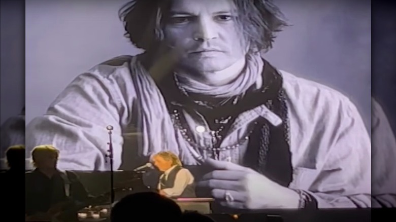 Paul McCartney performing, while a video in the background shows Johnny Depp playing guitar