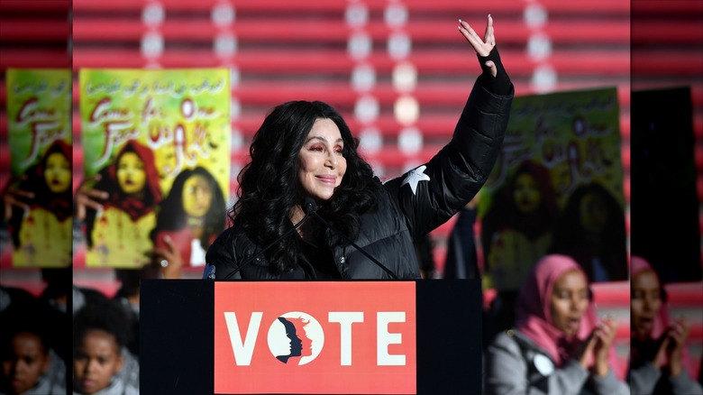 Cher smiling and waving at "Vote" podium