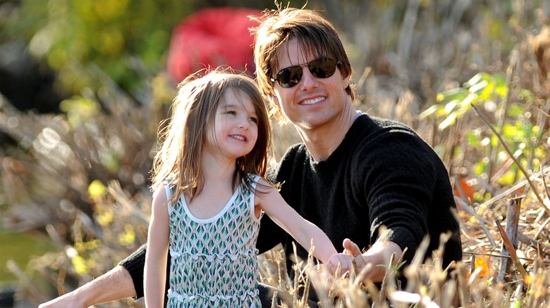 Tom and Suri Cruise sitting in a park