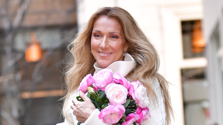 Celine Dion smiling while clutching a bouquet of flowers 