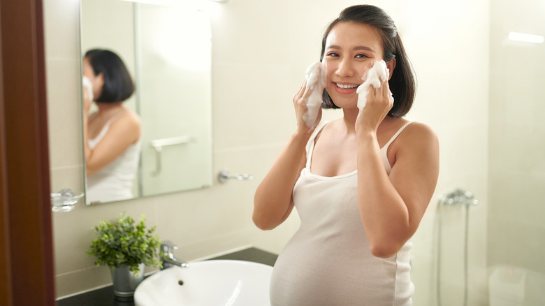 A pregnant woman washing her face