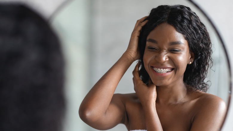 A smiling woman massaging her scalp 