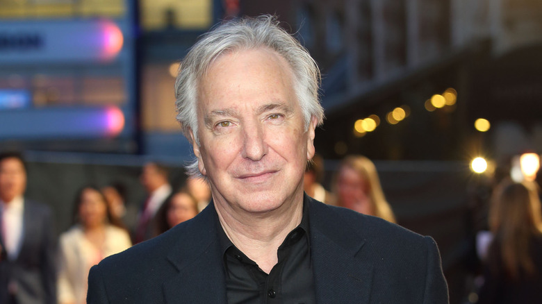 Alan Rickman slightly smiling in a black suit