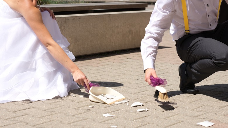 bride and groom sweeping broken dish