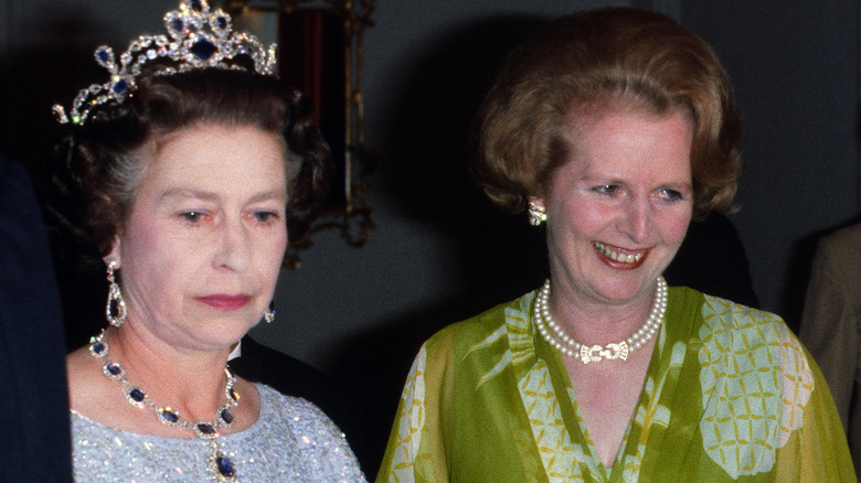 Queen Elizabeth stares stonily beside Margaret Thatcher