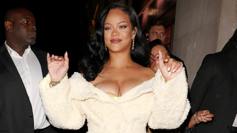 Rihanna wearing a cream, off-the-shoulder ensemble while waving