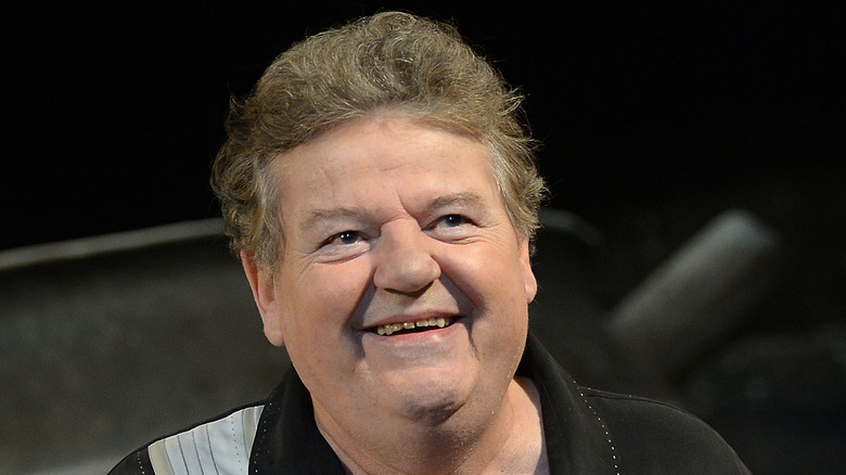 Robbie Coltrane smiles while doing an interview