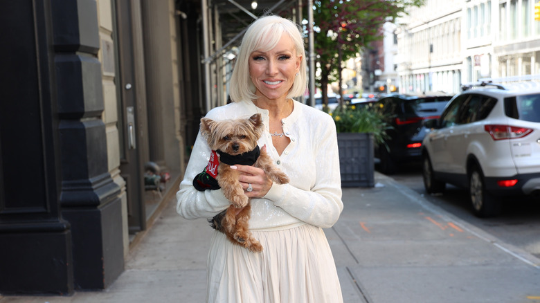 Margaret Josephs in white outfit holding a dog