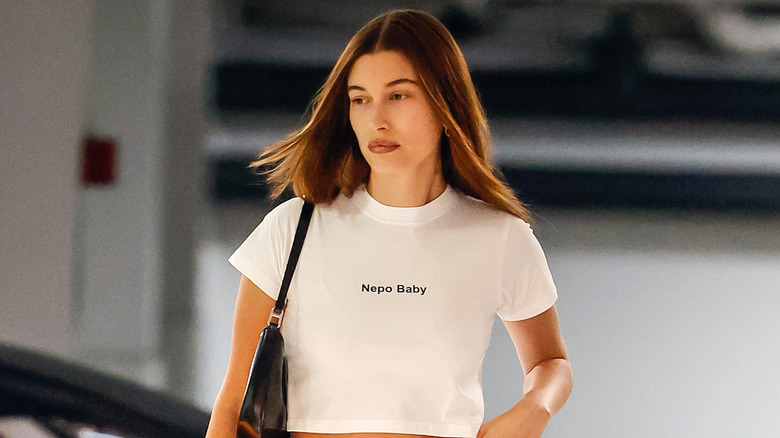 Hailey Bieber wearing a white crop top that says "Nepo Baby"